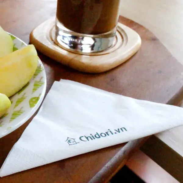 Khăn giấy cocktail đặt cạnh ly cà phê và đĩa trái cây